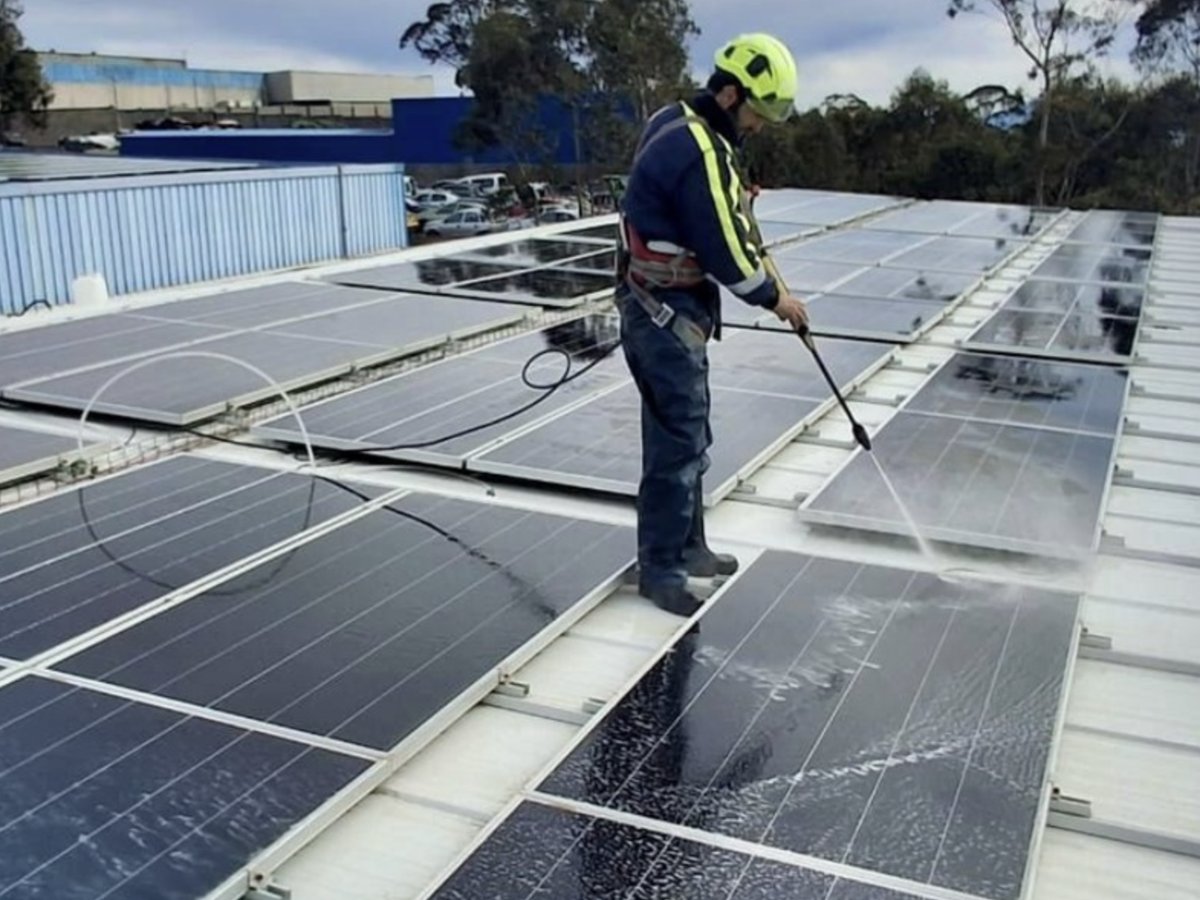 Técnico con equipo de seguridad realizando mantenimiento de paneles solares en el tejado